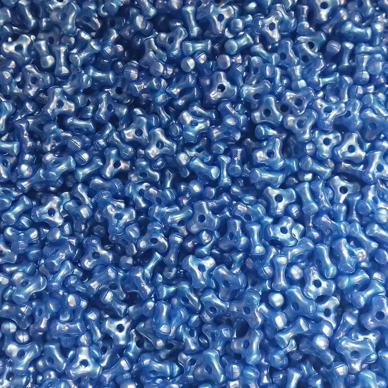 A close-up, top-down view of numerous small, glossy, tri beads dark blue pearl color beads with hole, filling the entire frame.